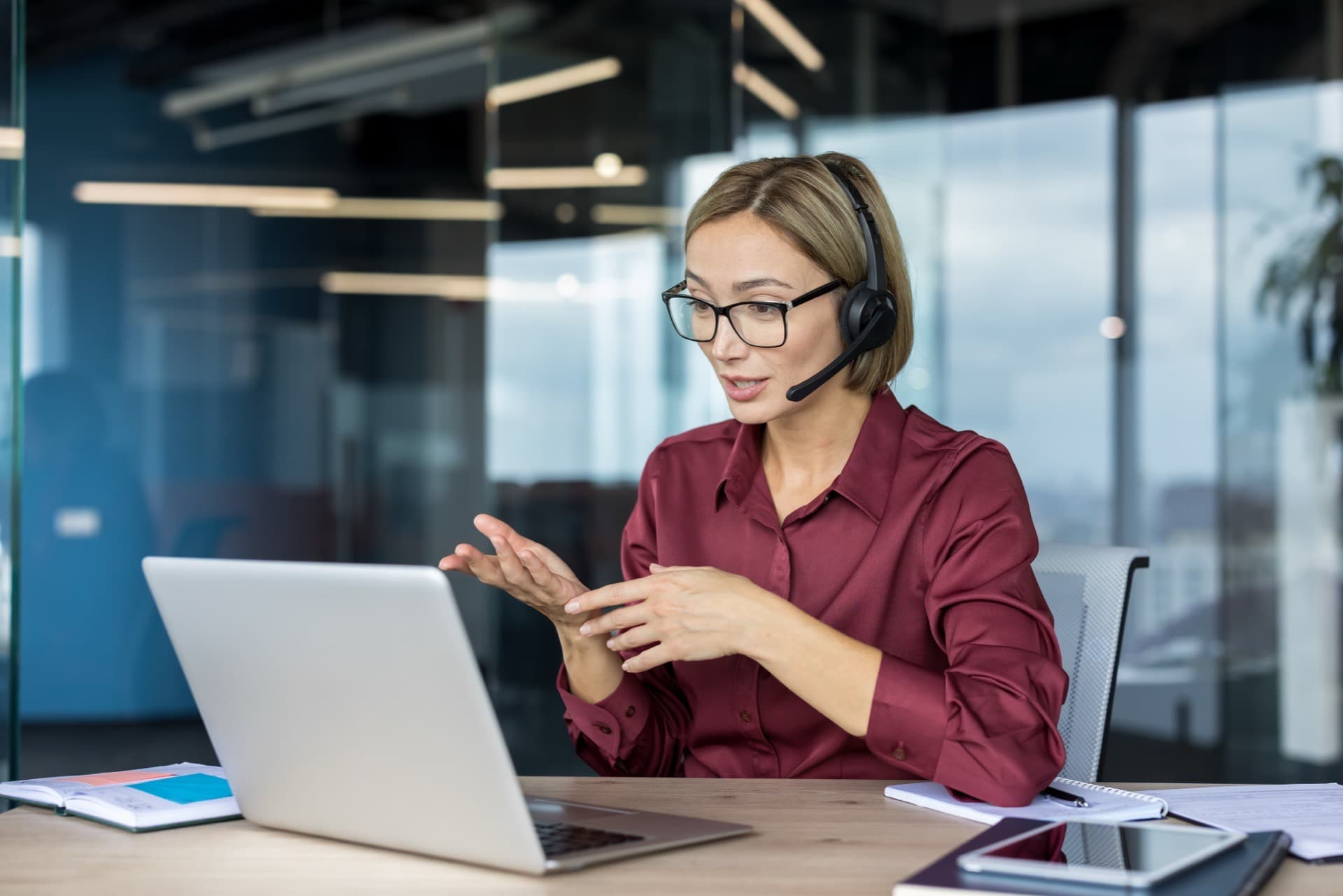 Mitarbeiterin im Kundenservice mit Headset am Laptop