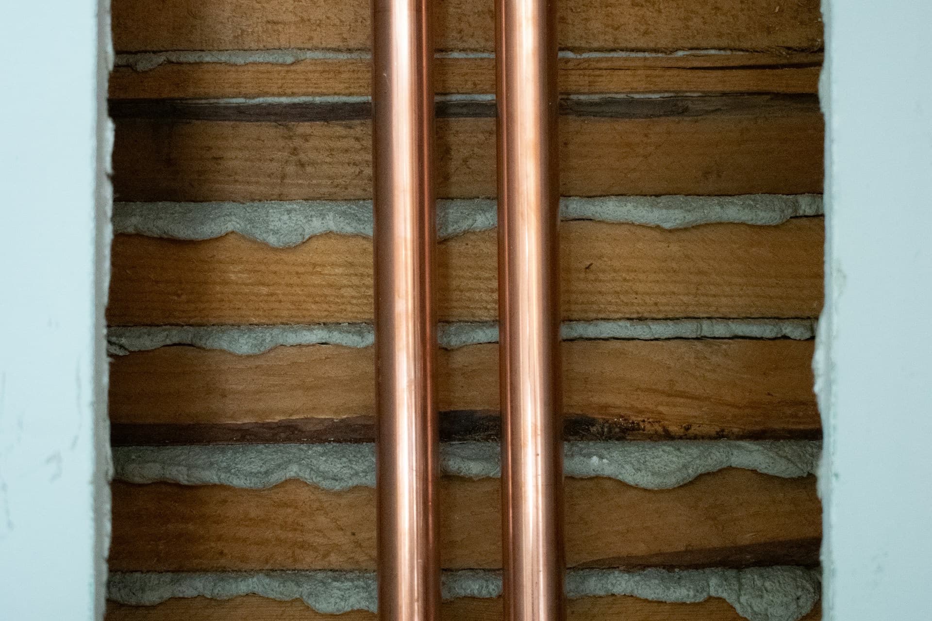 Freigelegte Kupfer-Wasserleitungen in einer geöffneten Wand