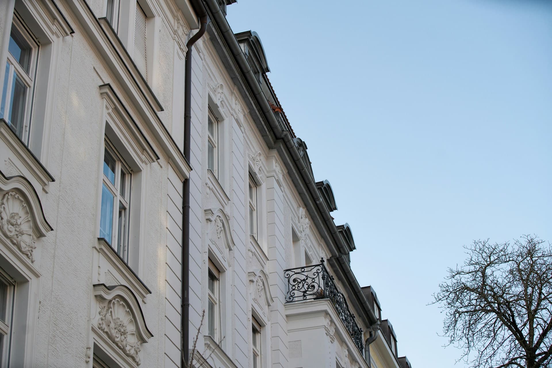 Weiße Altbaufassade eines Mehrfamilienhauses mit Balkon